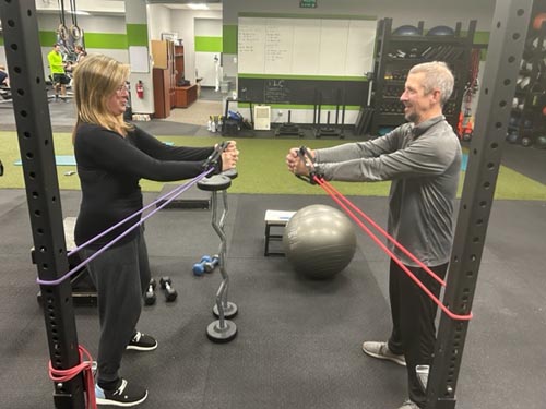 Buddy session personal training services with workout bands facilitated by Katie Plunkett of Optimize You Personal Training & Fitness.